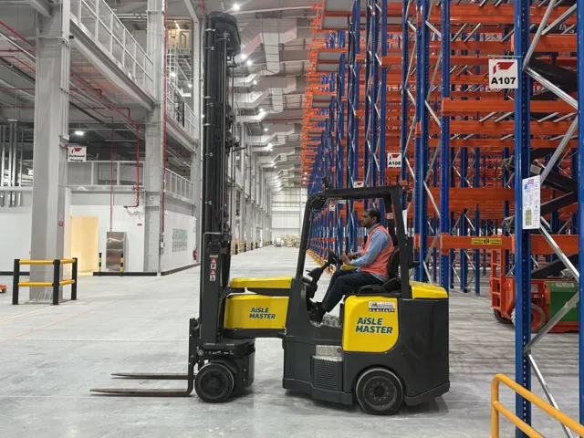 Aisle-Master articulated forklift with an operator in a high-bay racking warehouse