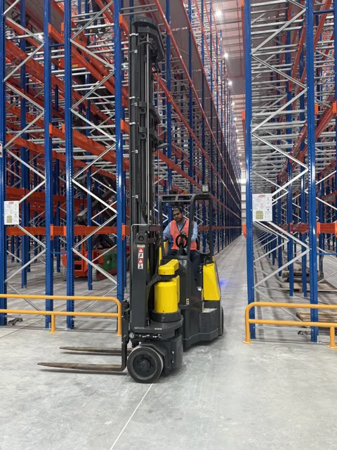 Aisle-Master articulated forklift with an operator in a narrow racking aisle