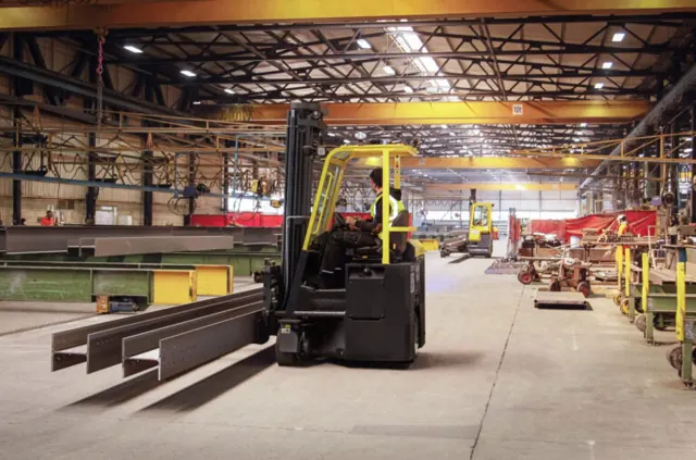 Combilift multidirectional forklift carrying long steel sections in a factory