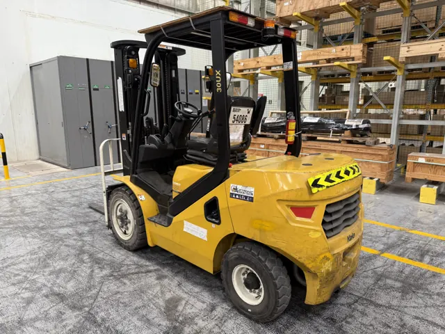 Yellow diesel forklift parked beside pallet racking, rear three-quarter view