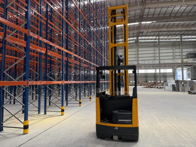 Electric reach truck in a racking aisle, seen from behind